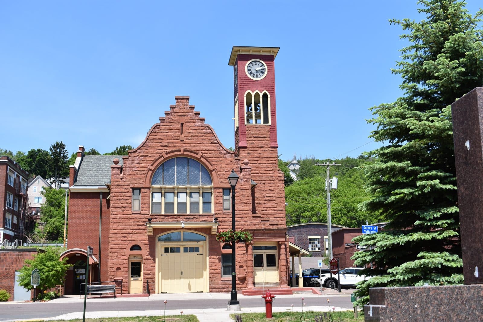 Sandstone clock tower building, Hancock MI | State Wide Real Estate of Houghton Red sandstone civic building with a clock tower and tall arched window in downtown Hancock, Michigan