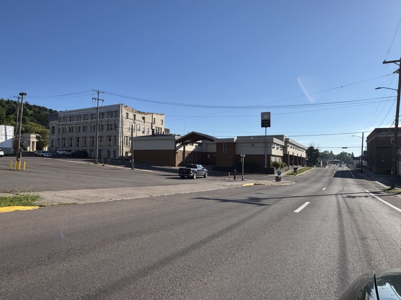 Downtown street, Hancock MI | State Wide Real Estate of Houghton A wide street through downtown Hancock, Michigan, with older commercial buildings and a wooded hill behind