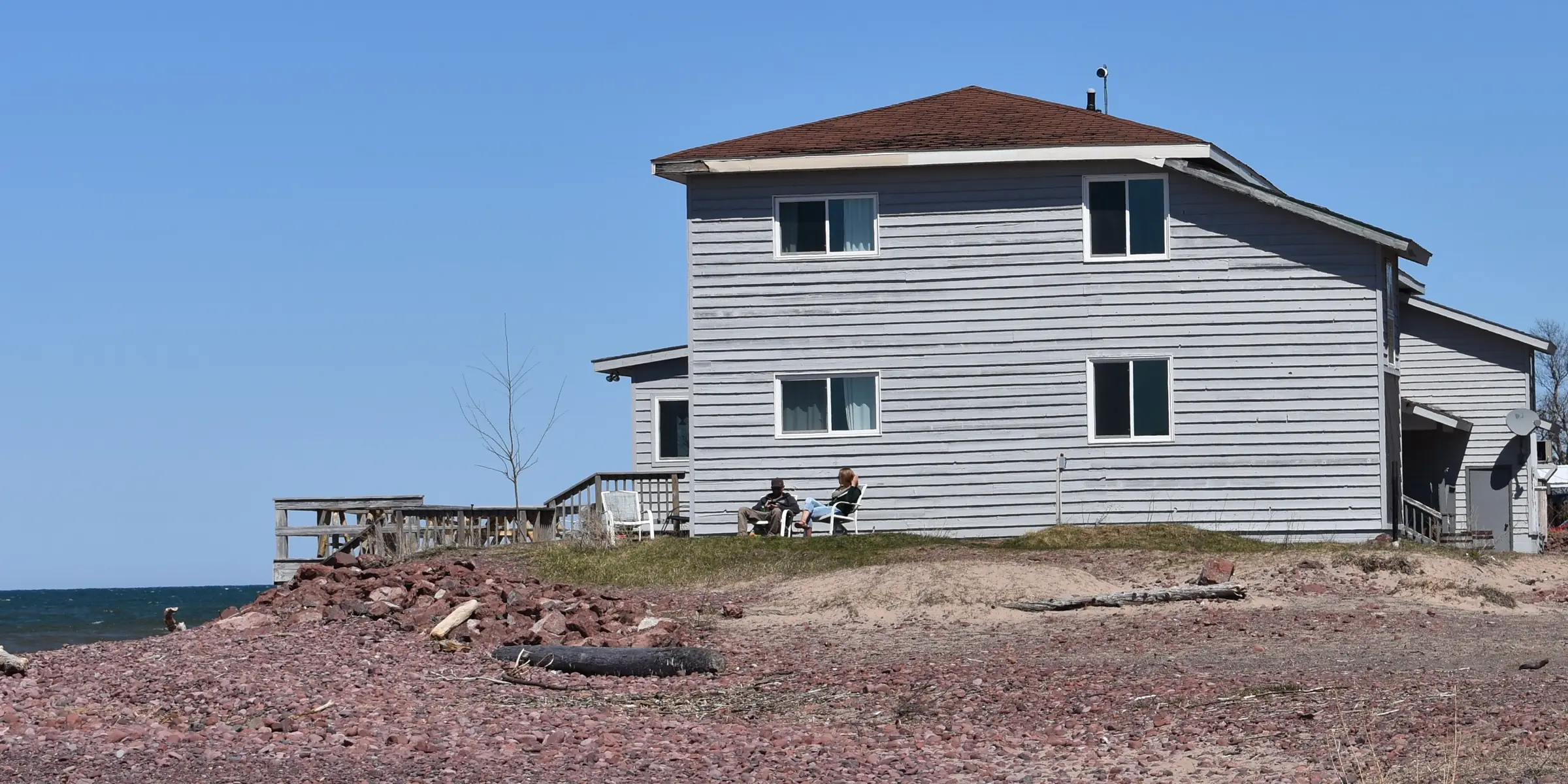 A two-story house on the Lake Superior shoreline at Eagle River, Michigan, with a pebble beach in front.
