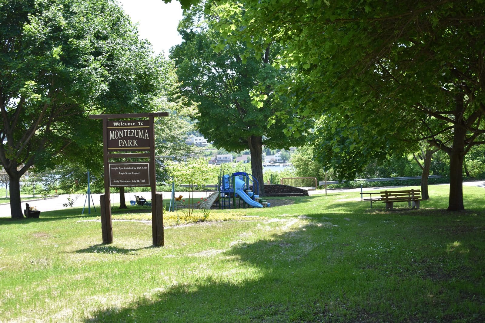 Montezuma Park, Hancock MI | State Wide Real Estate of Houghton Welcome sign, playground and benches at Montezuma Park in Hancock, Michigan, with Portage Lake behind