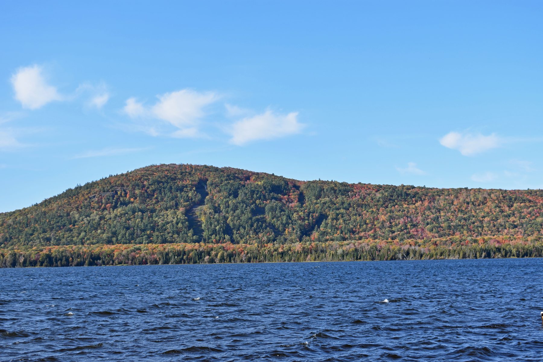 A hillside in fall color seen across open water in the Keweenaw
