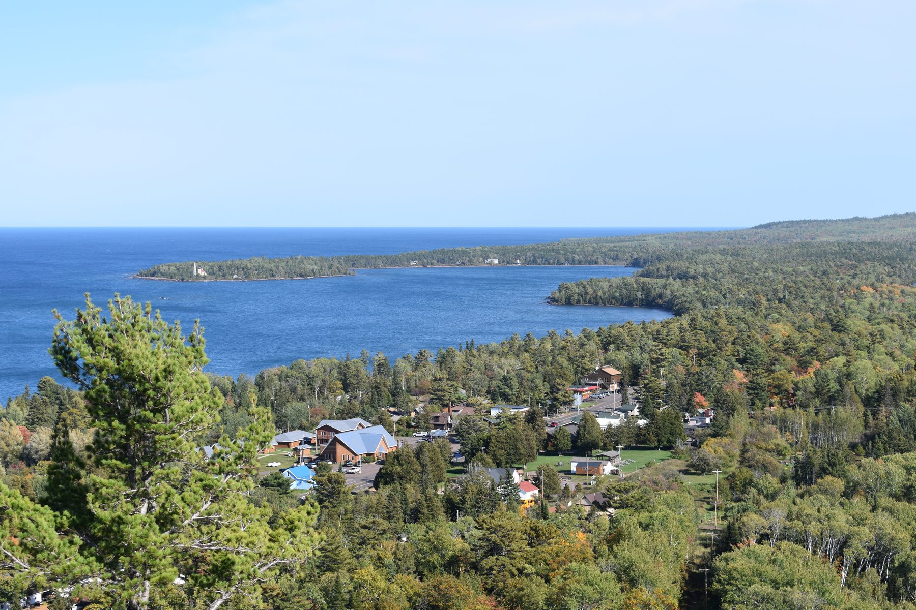 A shoreline village and Lake Superior seen from above during fall color