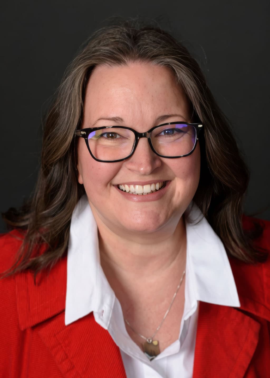 Jennifer Deephouse, REALTOR with State Wide Real Estate of Houghton, wearing a red jacket over a white collared shirt.
