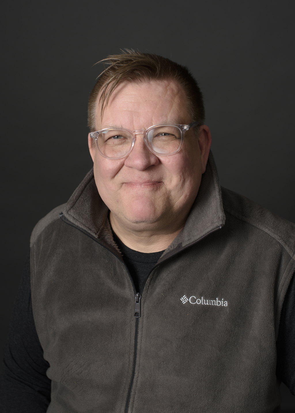 Kevin Liimatta, Associate Broker and owner of State Wide Real Estate of Houghton, wearing a brown fleece jacket against a gray studio backdrop.