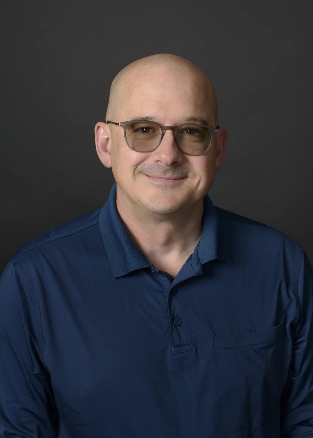 Michael Haanela, Sales Associate at State Wide Real Estate of Houghton, wearing a navy polo shirt against a gray studio backdrop.