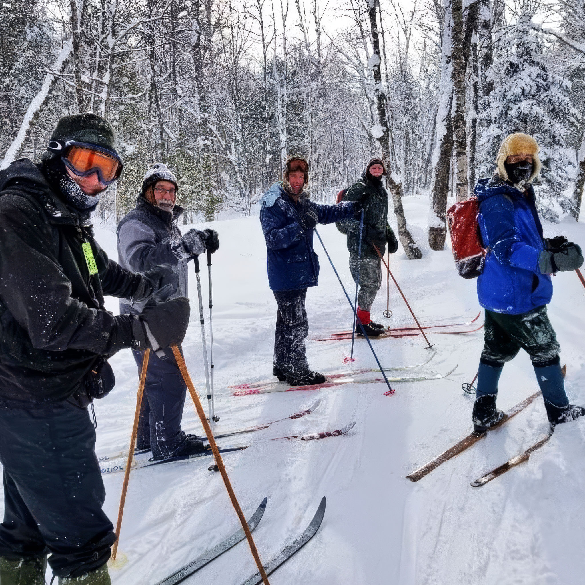 MTU Students in winter gear and backpacks stand on cross-country skis in a snowy forest, smiling and posing for the camera among tall trees covered in fresh snow.